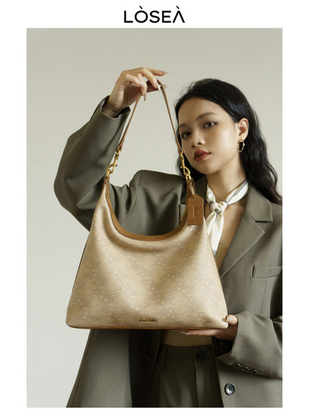 Beige monogram shoulder handbag held by a model