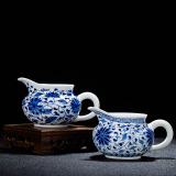 Jingdezhen hand - made ceramic fair cup of tea by hand and points tea exchanger with the ceramics cup against the hot cup of tea sea