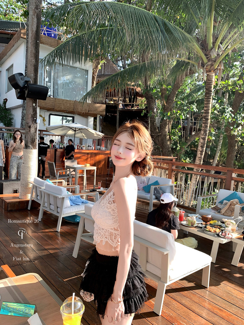 Woman wearing a white lace crop top and black ruffled skirt at a tropical resort