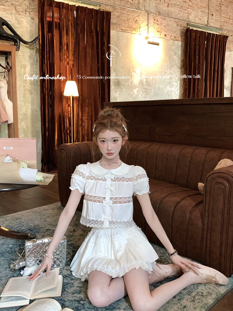 White lace-trimmed blouse and ruffled skirt set worn by a model