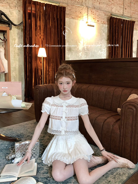 White lace-trimmed blouse and ruffled skirt set worn by a model