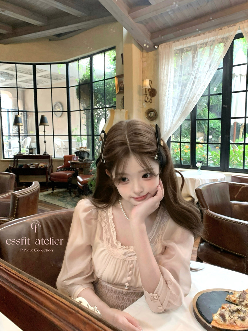Woman wearing a light beige lace-trim dress in a café setting