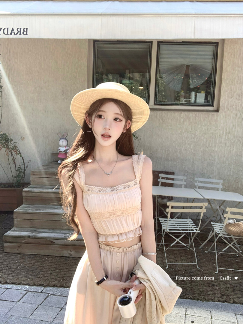 Woman wearing a light beige sleeveless lace-trim summer outfit and straw hat outdoors