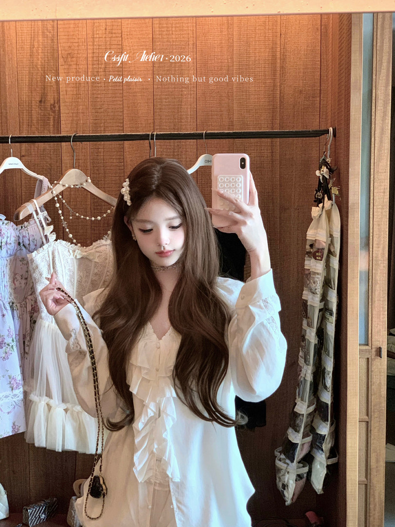 Woman wearing a white ruffled blouse in a clothing store mirror selfie