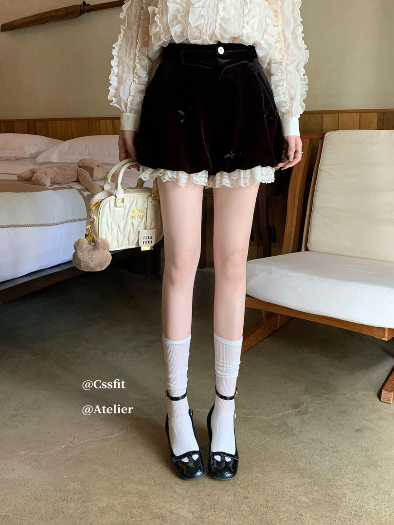 Model wearing a black mini skirt with a white ruffled blouse and heels