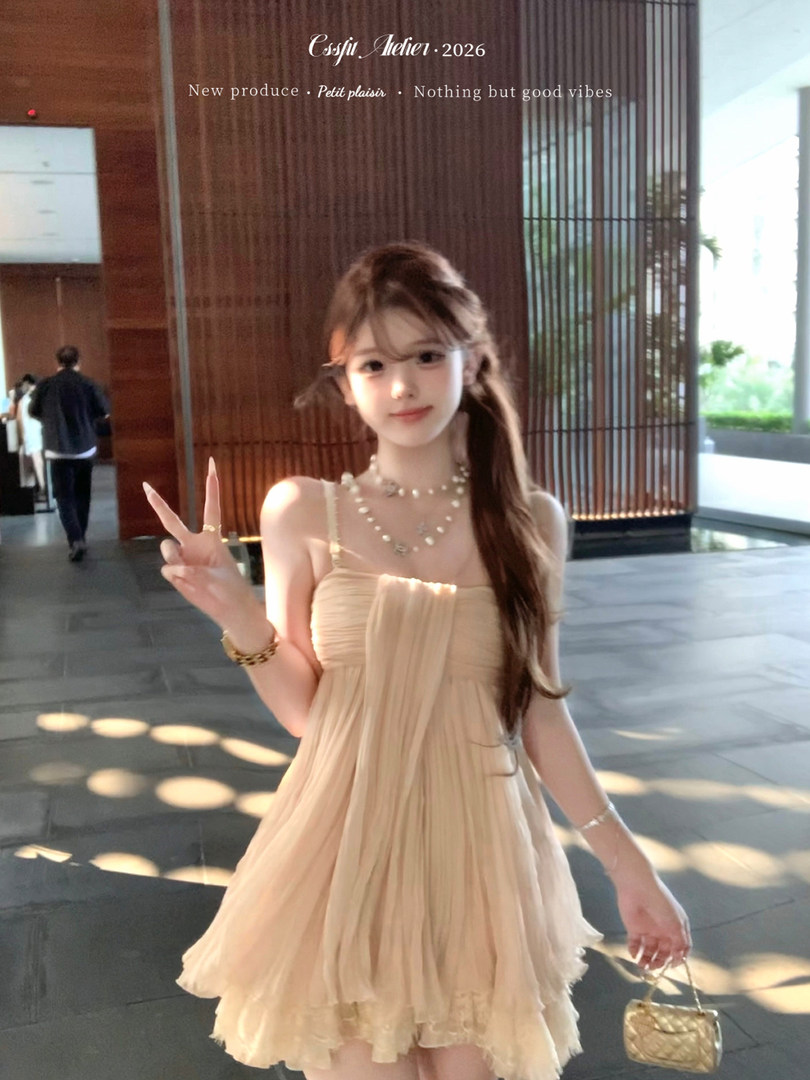 Model wearing a beige strapless pleated mini dress with pearl accessories
