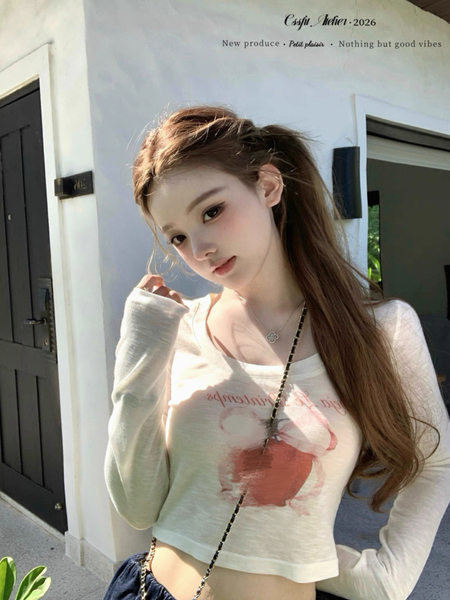 Model wearing a white long-sleeve crop top with a red graphic print