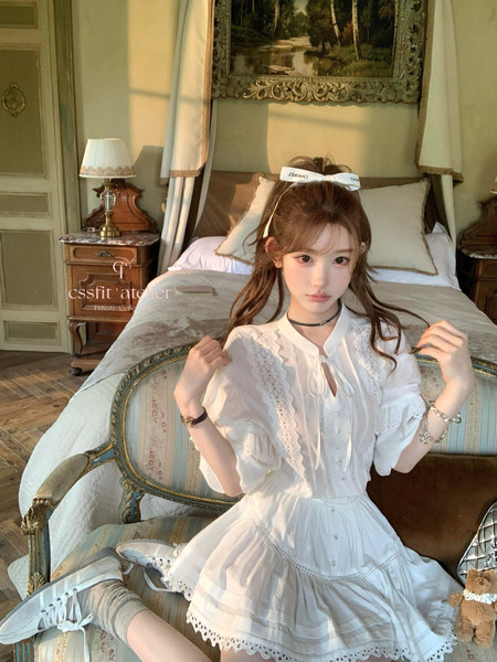 Woman wearing a white lace dress and white sneakers in a vintage-style bedroom