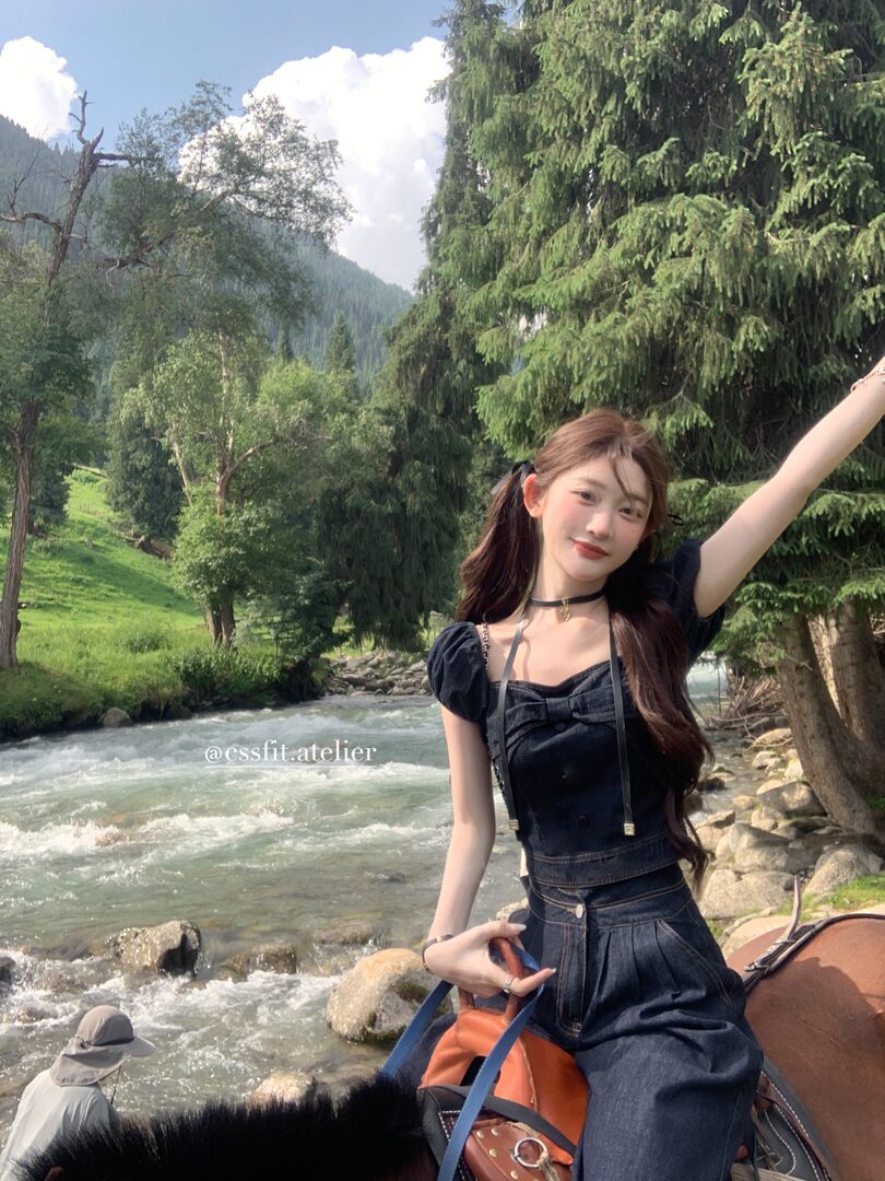 Woman wearing a black denim two-piece outfit outdoors by a river