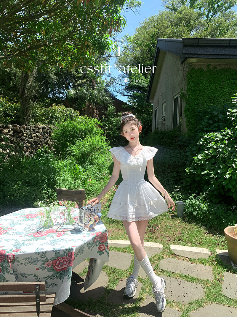 White feminine short dress worn outdoors in a garden setting