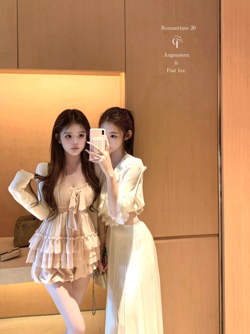 Mirror selfie of two women wearing light pink and white feminine outfits