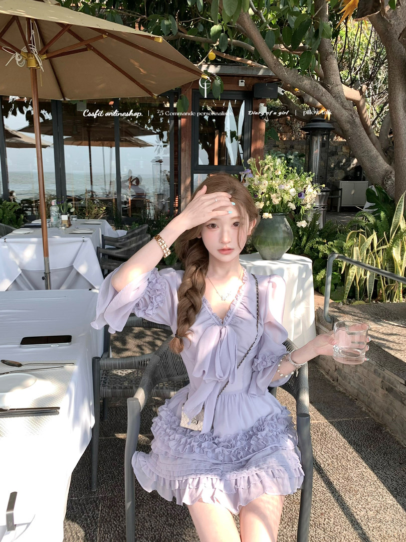 Woman wearing a lavender ruffled dress at an outdoor seaside restaurant