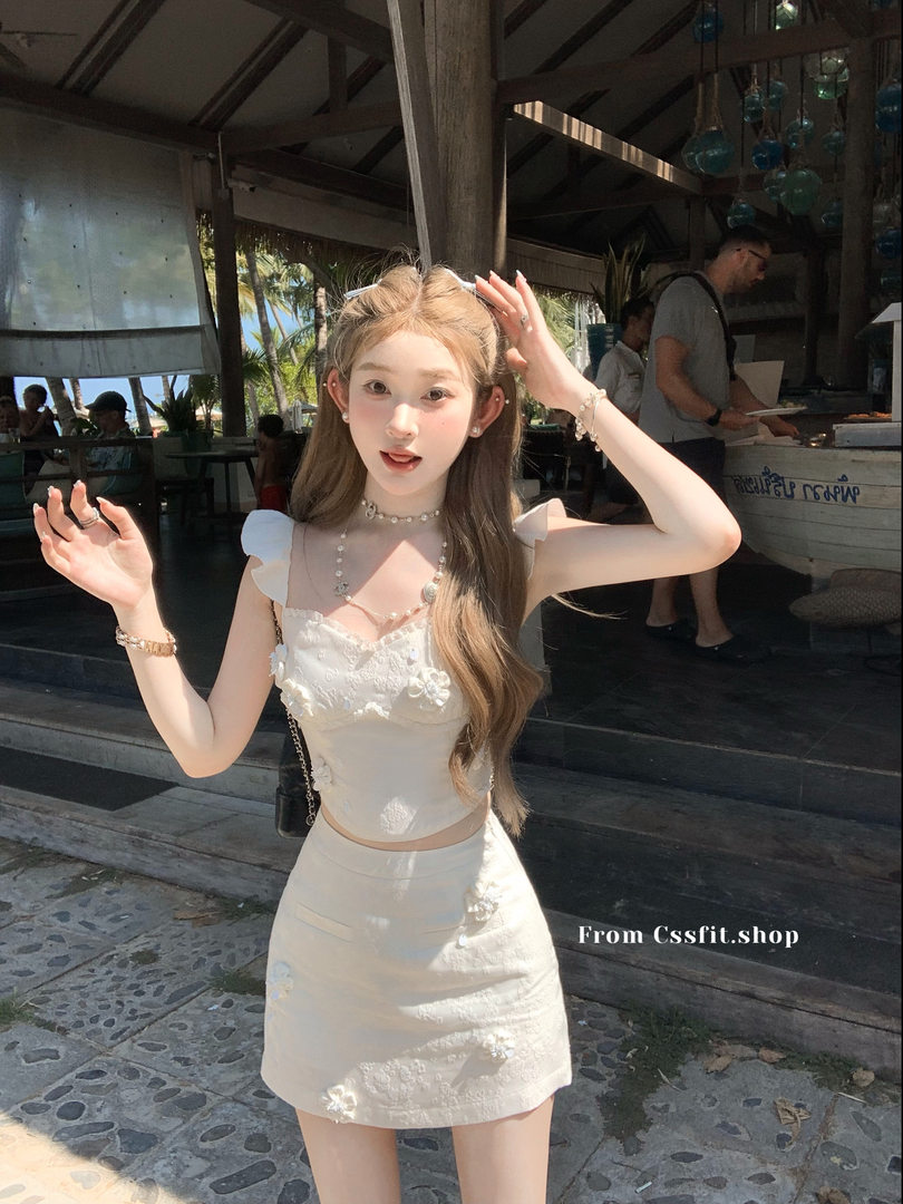 Model wearing a white embellished two-piece outfit outdoors