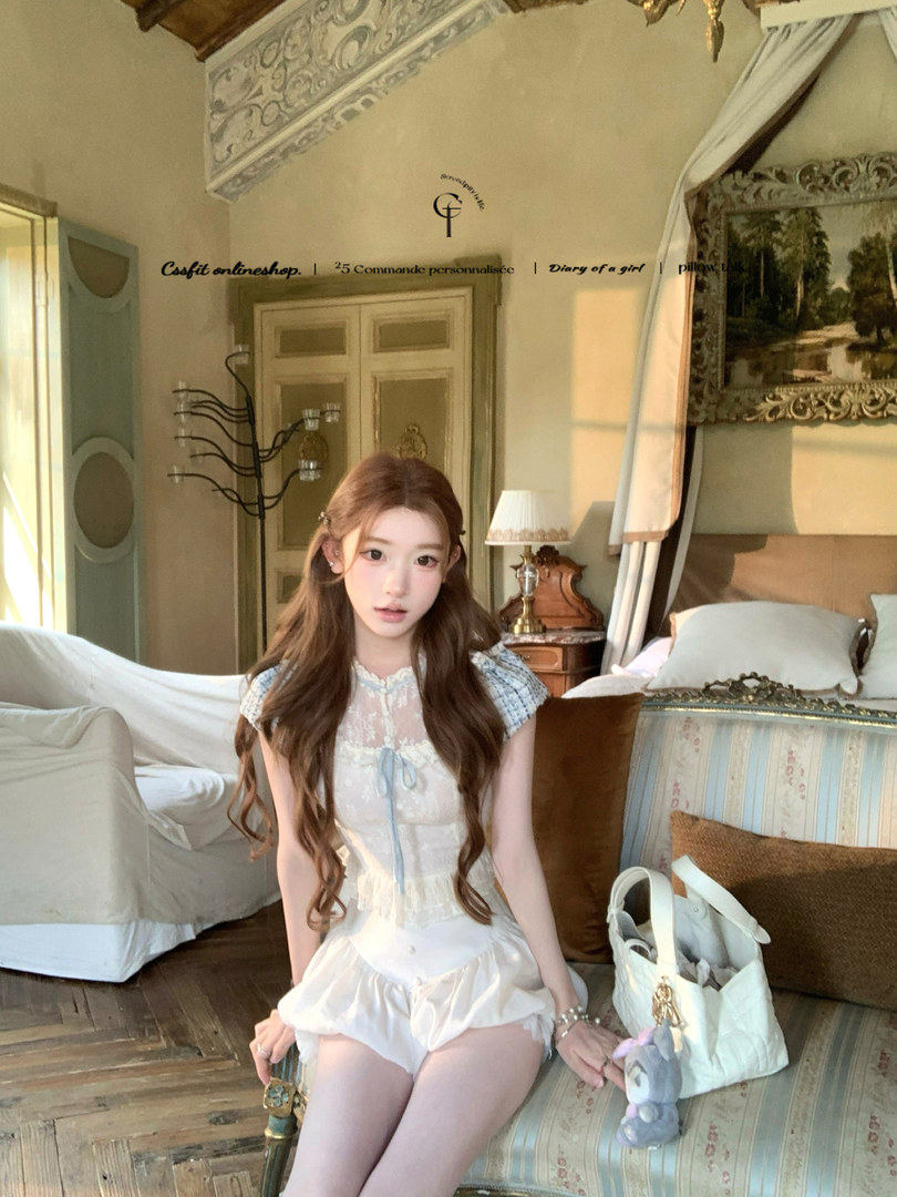 Young woman wearing a light blue and white lace dress/romper in a vintage-style bedroom