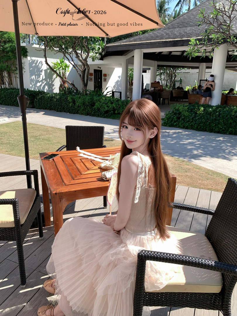 Woman wearing a pink tulle dress seated at an outdoor resort table
