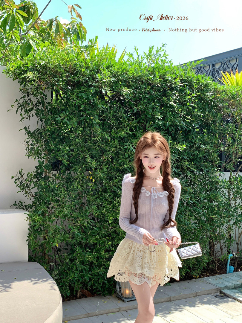 Model wearing a light lavender lace-trim top with a cream lace mini skirt and silver quilted handbag outdoors