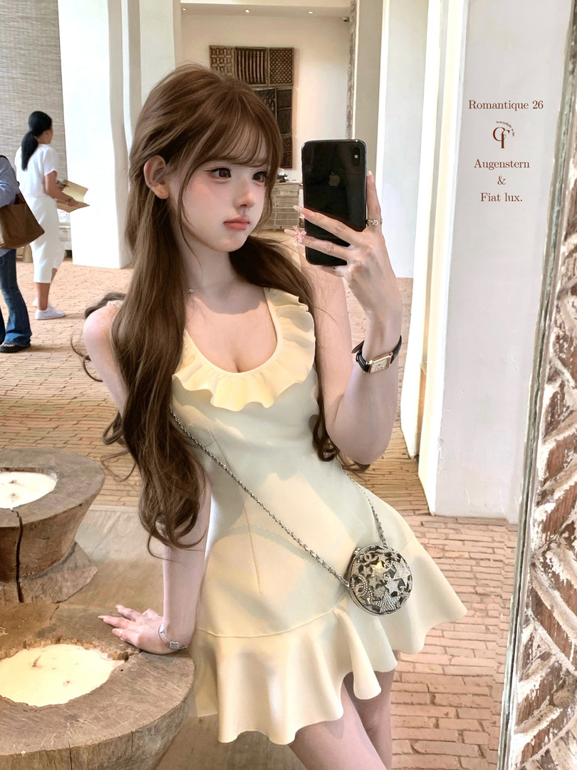 Woman wearing a pale yellow ruffled sleeveless dress in a mirror selfie