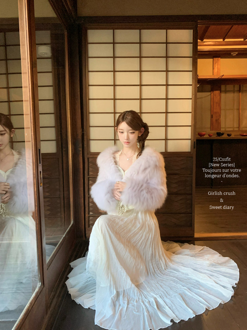 Woman wearing a white pleated gown with a fluffy light-colored shawl