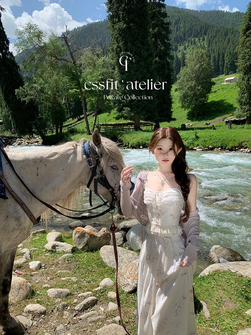 Woman wearing a light floral dress outdoors beside a horse and river