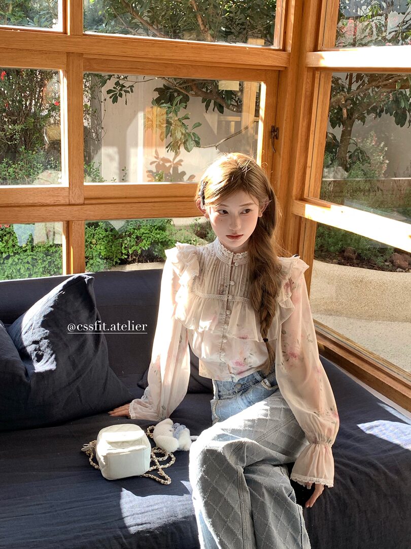 Model wearing a sheer ruffled long-sleeve blouse with jeans
