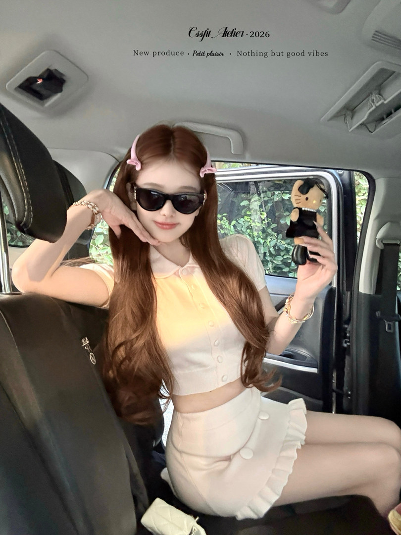 Model wearing a cream button-front crop top and ruffled mini skirt in a car