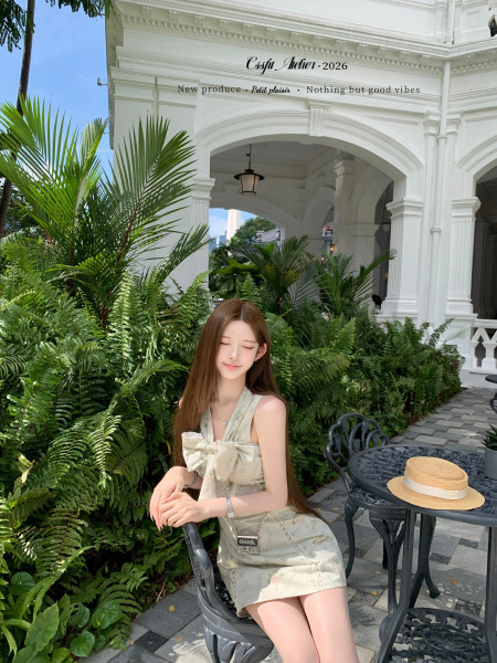 Woman wearing a light floral sleeveless dress outdoors in a tropical courtyard