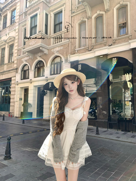 Woman wearing a white lace dress and straw hat outdoors