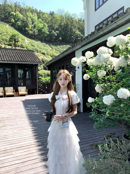 Woman wearing a white layered dress outdoors on a sunny patio