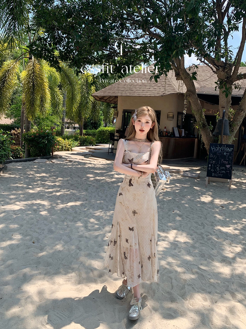 Young woman wearing a light beige floral midi dress on a sandy beach setting