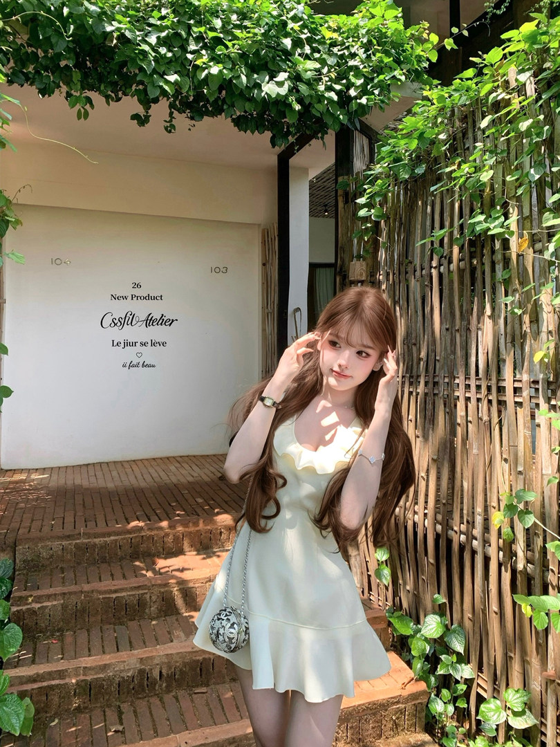 Woman wearing a light cream sleeveless dress outdoors