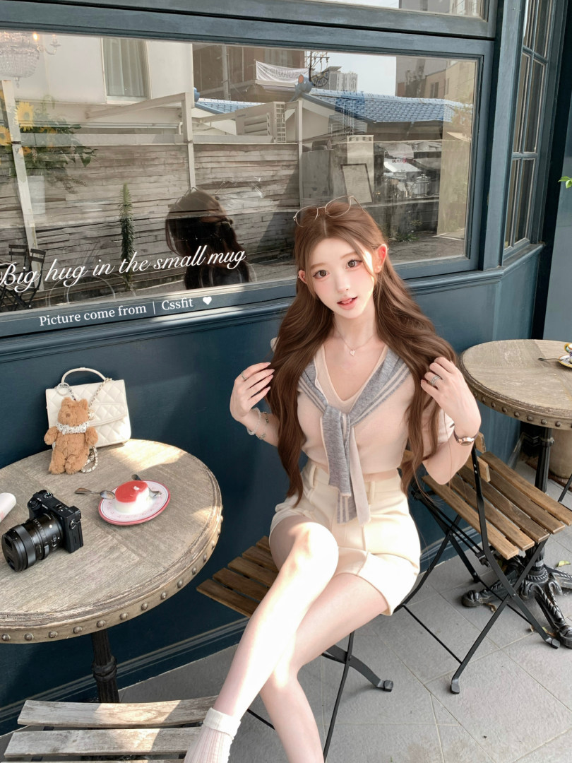 Young woman wearing a light beige knit top and shorts set in a café