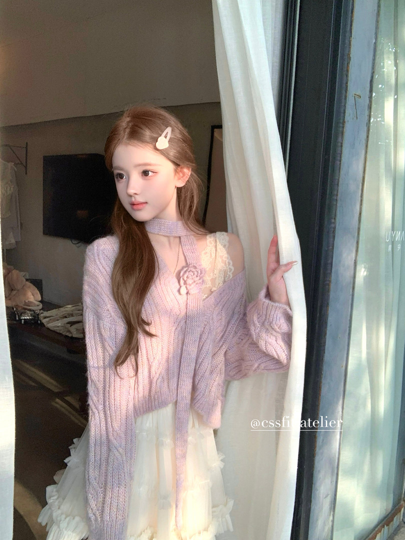 Model wearing a pastel lavender knit cardigan over a light dress by a window