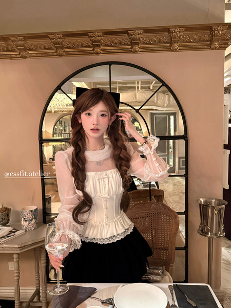 Woman wearing a white lace corset-style blouse with sheer sleeves