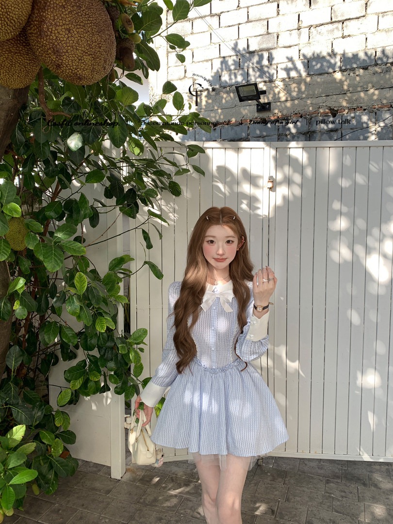 Model wearing a light blue bow-front dress outdoors