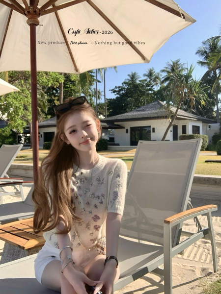 Young woman wearing a light floral knit top at a beach resort