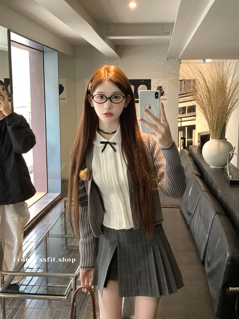 Woman wearing a preppy gray cardigan and pleated skirt outfit