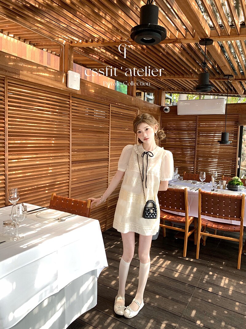 Cream short-sleeve dress worn by a model in a restaurant setting