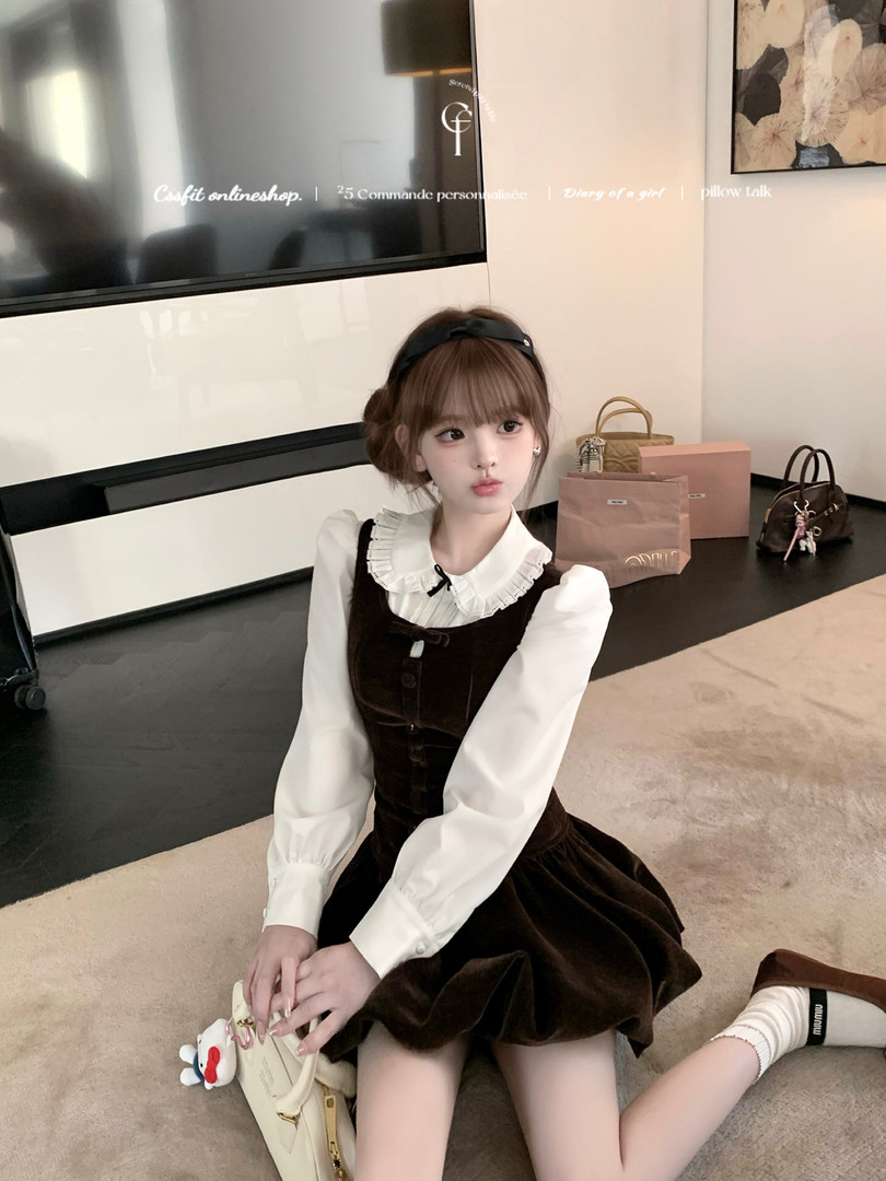 Young woman wearing a dark brown pinafore dress over a white ruffled blouse