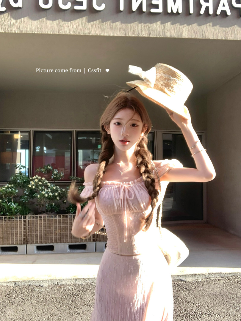 Model wearing a light pink off-shoulder dress and straw hat outdoors