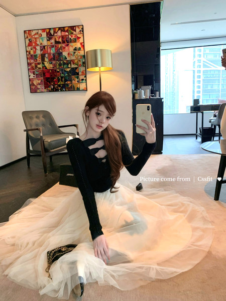 Woman wearing a black long-sleeve top with a white tulle skirt in a mirror selfie