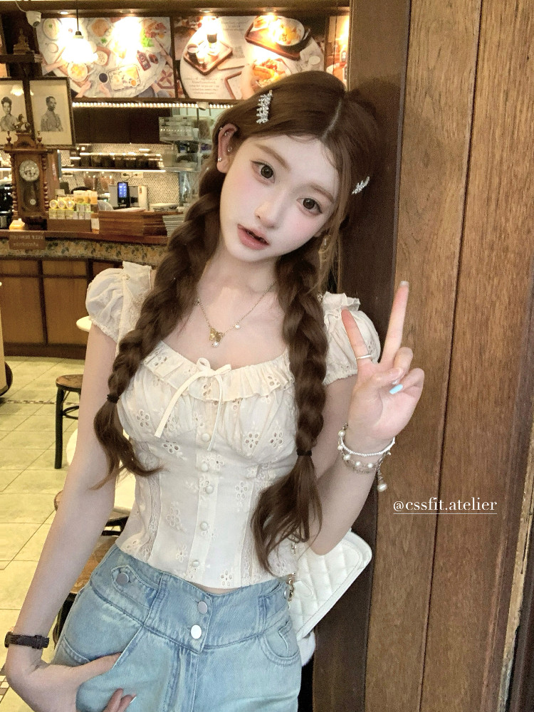 Woman wearing a white lace corset-style top with light blue jeans