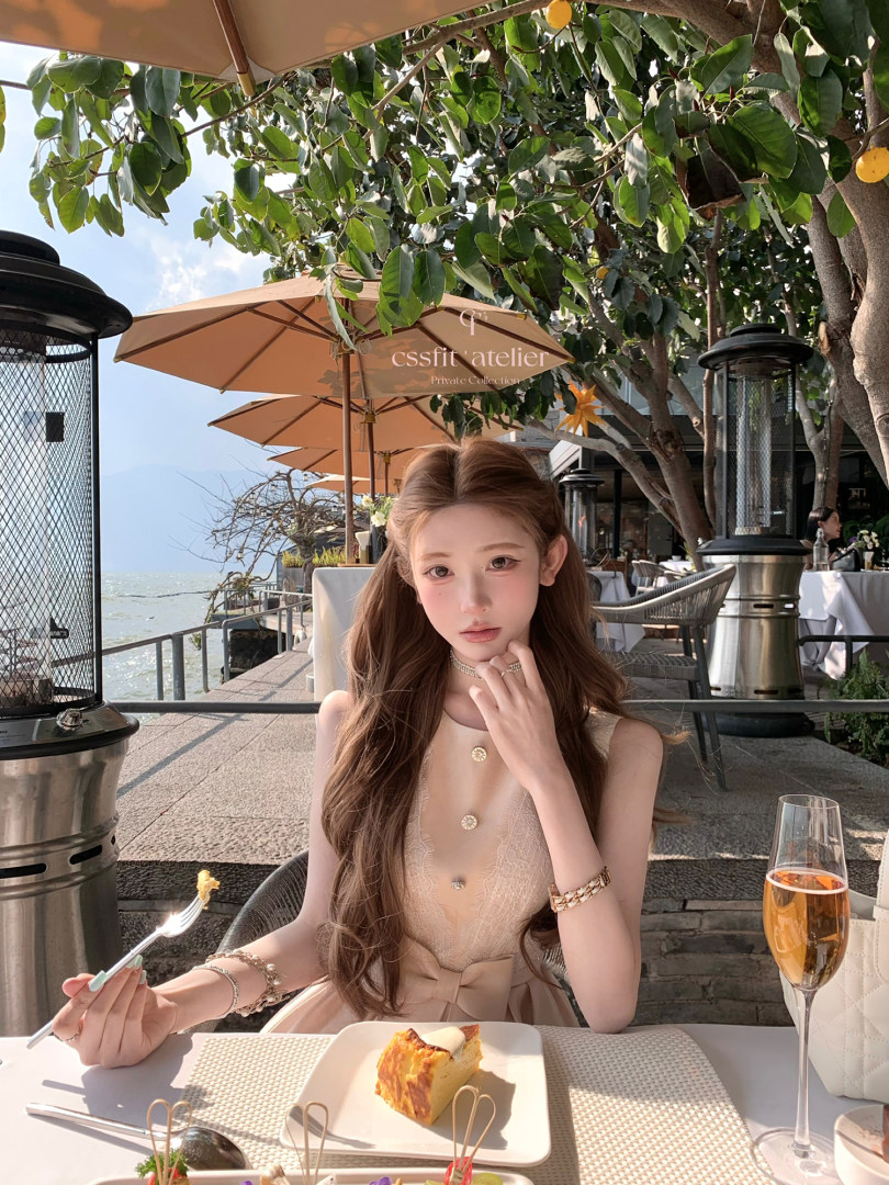 Woman wearing a beige elegant dress at an outdoor seaside restaurant
