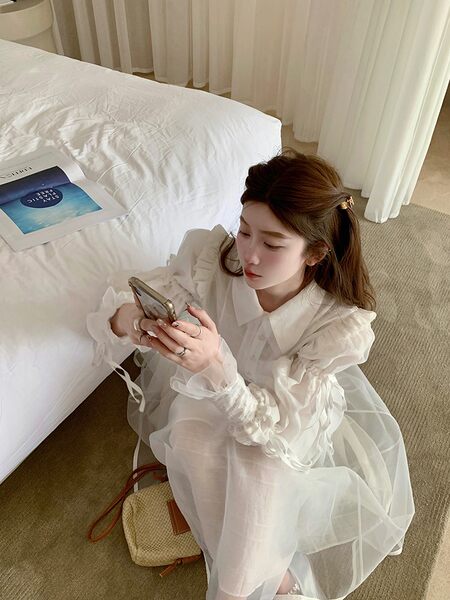 Woman wearing a white sheer long-sleeve dress indoors