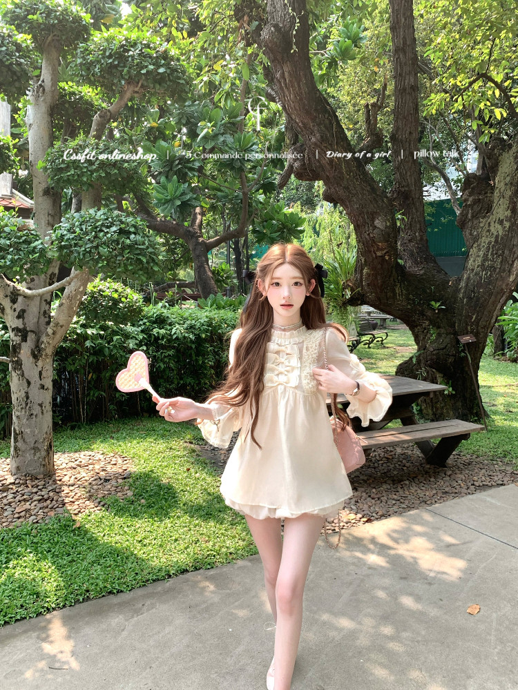 Cream feminine babydoll dress worn by a model outdoors in a park