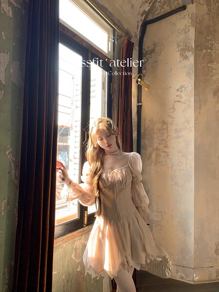 Woman wearing a light beige puff-sleeve dress by a window
