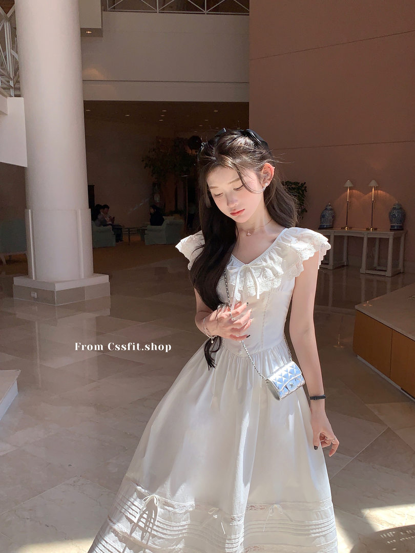 Woman wearing a white ruffled sleeveless dress with a small crossbody bag