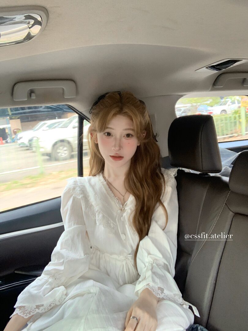 White long-sleeve lace dress worn by a model in a car