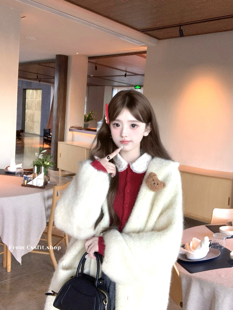 Model wearing a white fuzzy coat over a red dress in a cafe