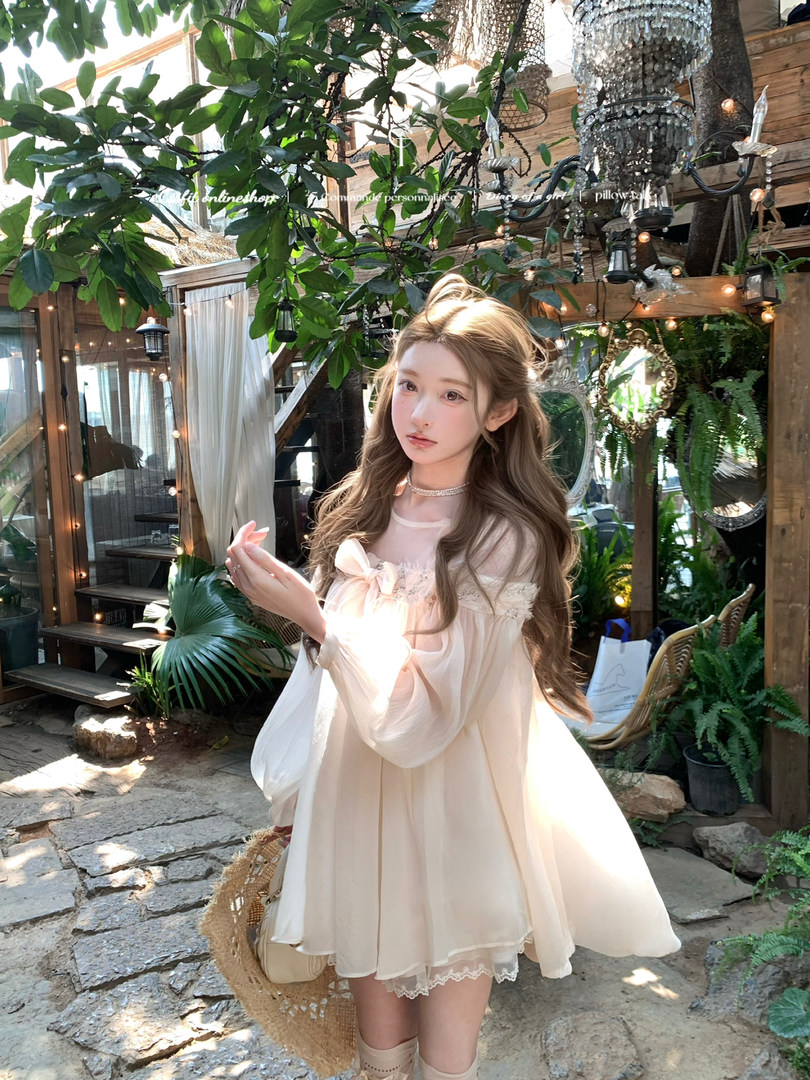 Woman wearing a light cream sheer dress outdoors in a garden setting