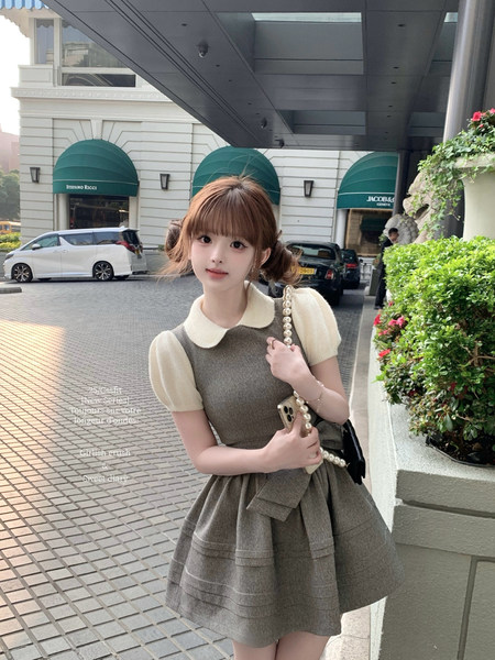 Young woman wearing a gray short-sleeve dress with a white Peter Pan collar outdoors